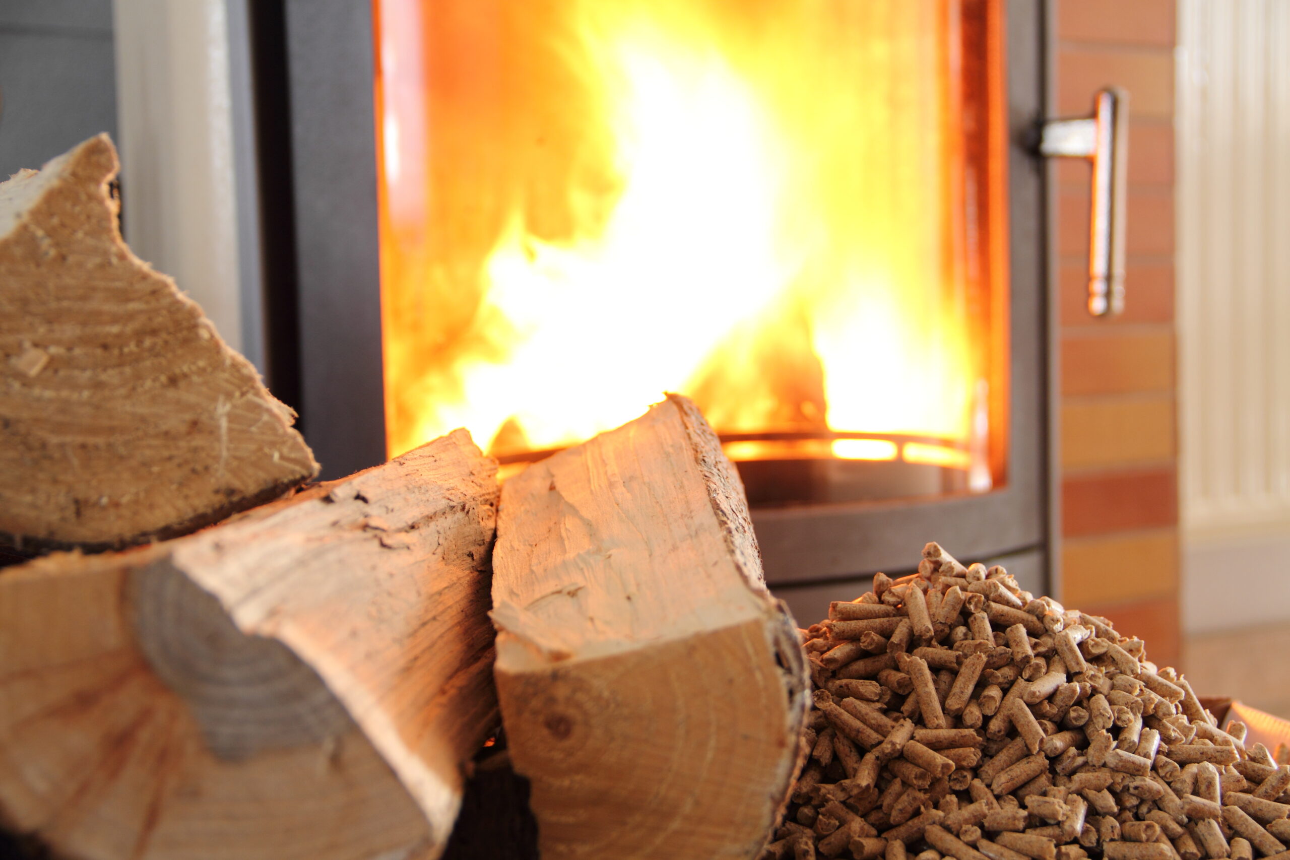 Pellets et buches devant un poêle à bois allumé