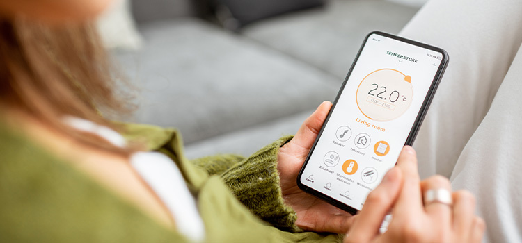 Femme qui contrôle le thermostat d'ambiance via une application